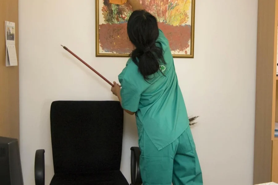 A cleaner dusting a picture.