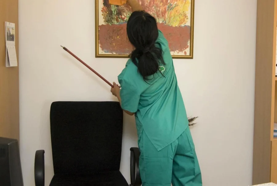 A cleaner dusting a picture.