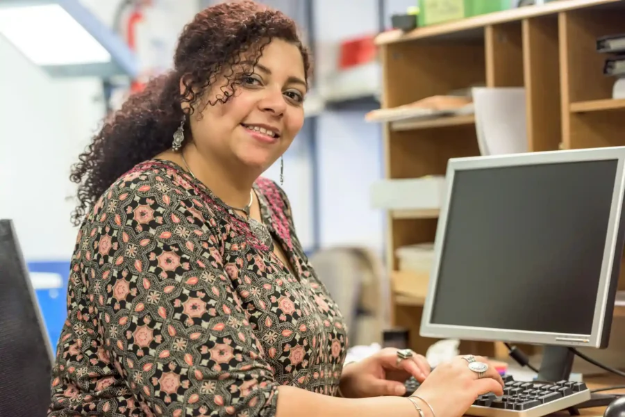 Women working on computer and smiling at camera