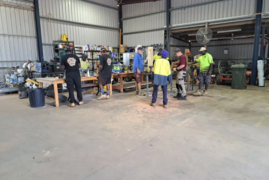 A group of First Nations men in a tin shed working on different pieces of word to hone their carpentry skills