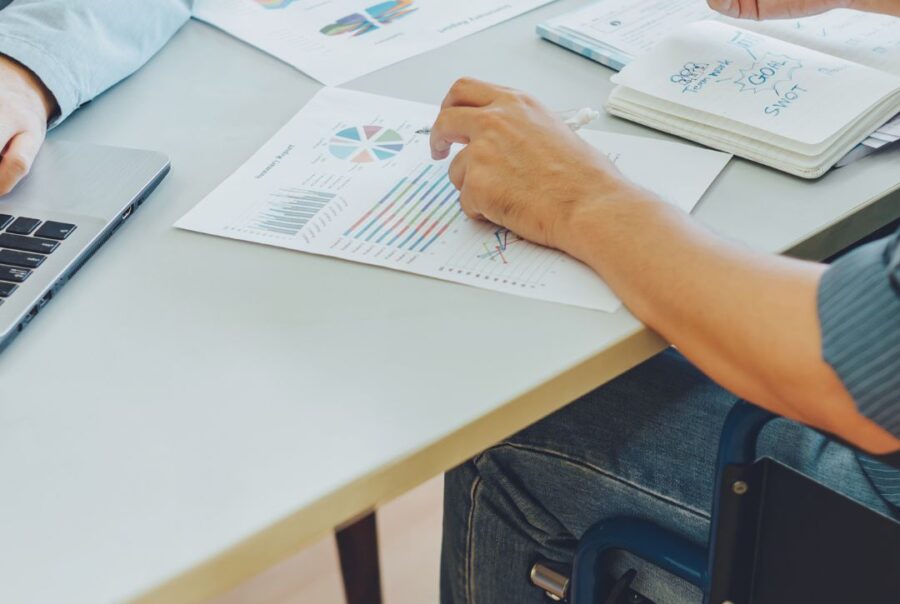 A person with disability sits at a desk working on goals and career aspirations with another person.