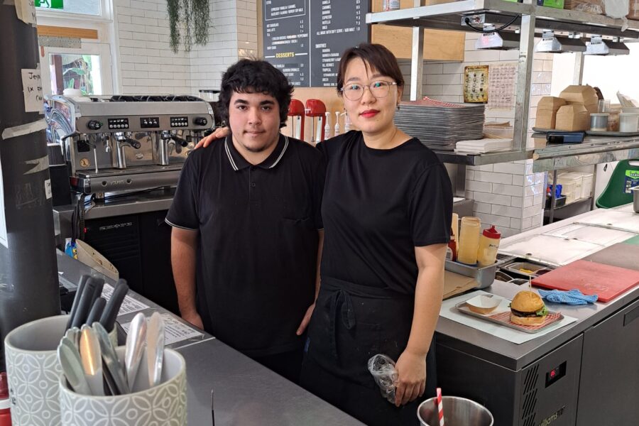 Image of a woman and a newly employed young man standing together facing the camera.