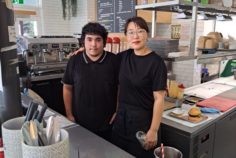 Image of a woman and a newly employed young man standing together facing the camera.