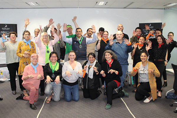 SIA team dressed colourfully smile and wave at the camera.