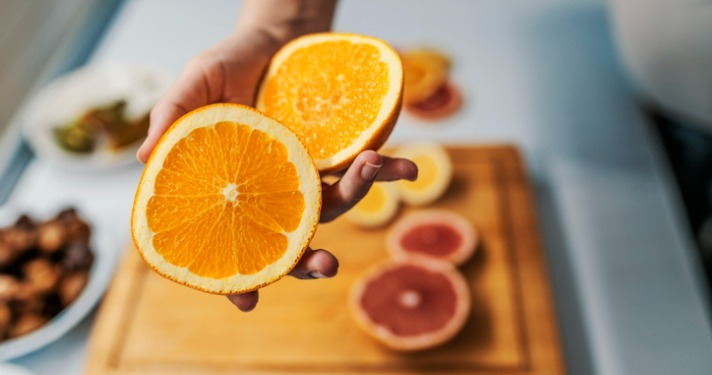 Female hand holding fresh Orange in her kitchen. Home grown ripe clementines