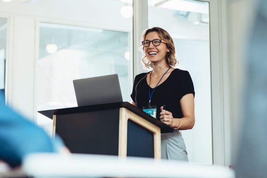 Businesswoman standing at podium with laptop giving a speech