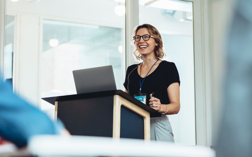 Businesswoman standing at podium with laptop giving a speech