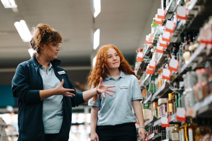 A retail store manager discussing daily targets and training with an assistant sales associate on the shop floor.