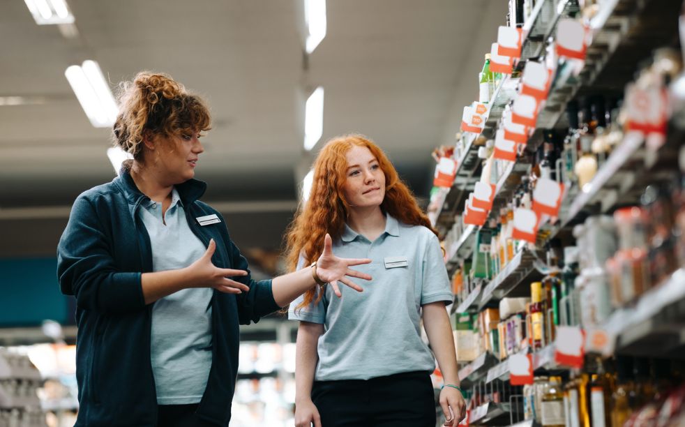 A retail store manager discussing daily targets and training with an assistant sales associate on the shop floor.