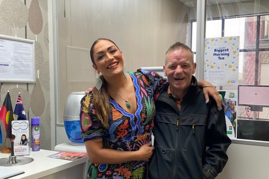 Tim smiling happily alongside his AKG job coach, Michele, who has her arm around his shoulder in a brightly lit office setting