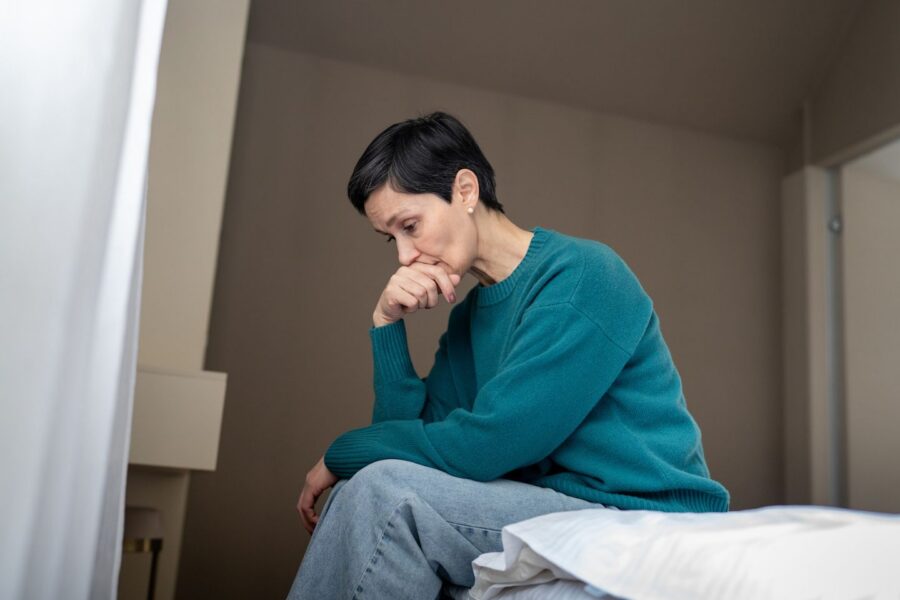 overwhelmed woman in despair on bed staring downward
