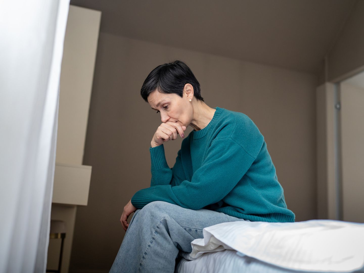 overwhelmed woman in despair on bed staring downward