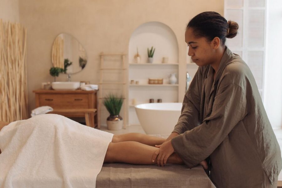 A massage therapist providing a leg massage to a client in a calm, modern spa setting in Cairns.
