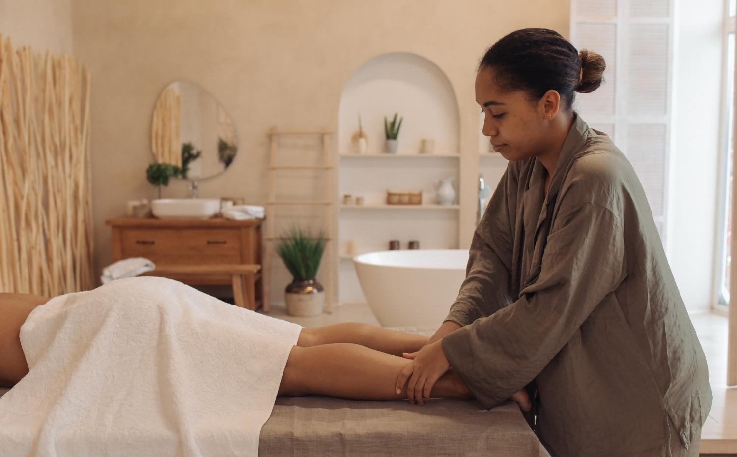 A massage therapist providing a leg massage to a client in a calm, modern spa setting in Cairns.