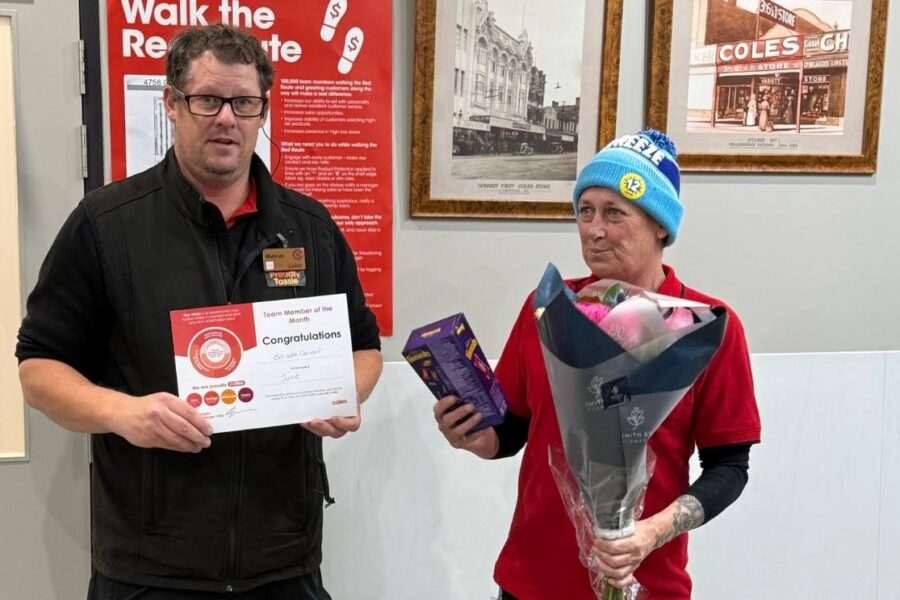 Belinda receiving her Employee of the Month award certificate, chocolates, and flowers from a Coles store manager