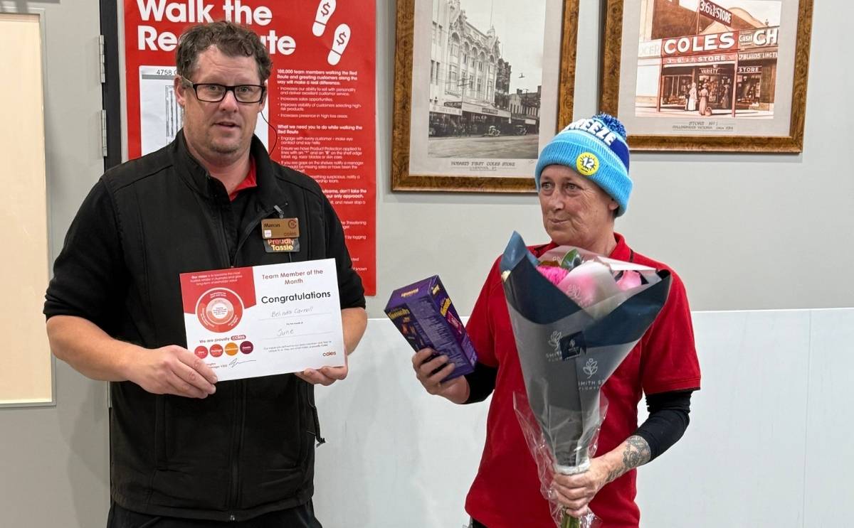 Belinda receiving her Employee of the Month award certificate, chocolates, and flowers from a Coles store manager